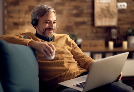 Happy businessman drinking tea and using laptop in the evening a